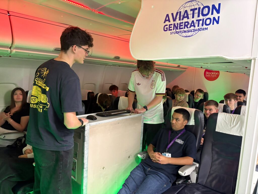 Students in the Aviation Generation cabin at Stockton Sixth Form College, one at the galley cart and others in passenger seats.